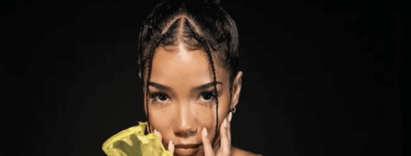 Woman with braided hair holding yellow flower.